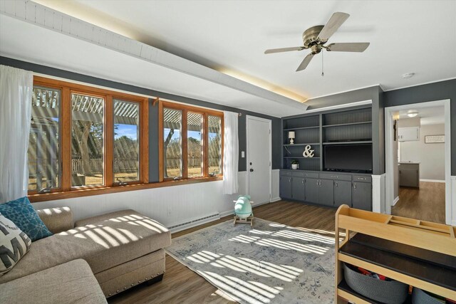 living area featuring ceiling fan, baseboards, a baseboard heating unit, and dark wood-type flooring