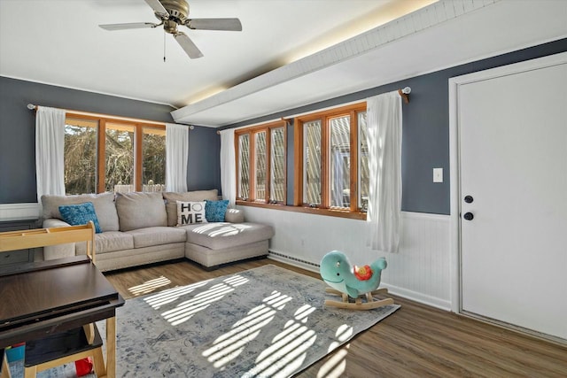 living area with a wainscoted wall, a baseboard radiator, ceiling fan, and wood finished floors