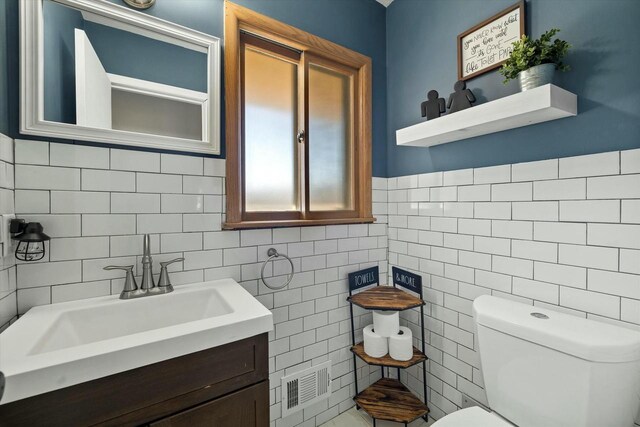 bathroom with tile walls, visible vents, toilet, and vanity