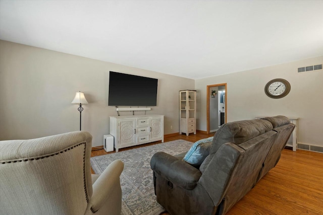 living room with visible vents, baseboards, and wood finished floors