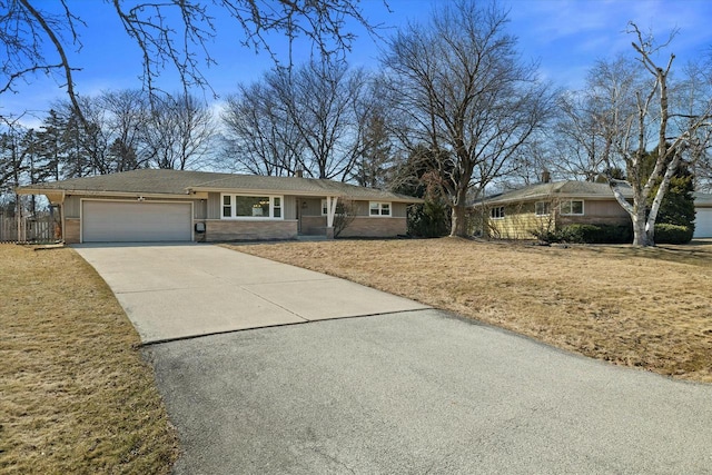 single story home with stone siding, a front yard, concrete driveway, and an attached garage