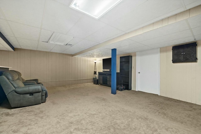 living area featuring wooden walls, a paneled ceiling, and carpet