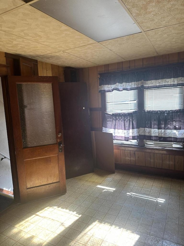 kitchen with light floors, wooden walls, and a drop ceiling