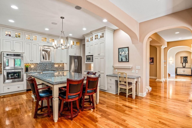 dining space with baseboards, decorative columns, recessed lighting, arched walkways, and light wood-type flooring