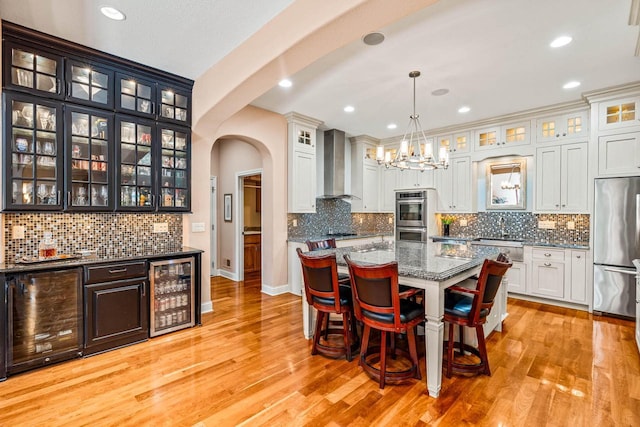 dining space featuring beverage cooler, arched walkways, and light wood finished floors