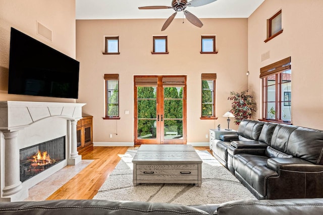 living area with a high end fireplace, a healthy amount of sunlight, light wood-type flooring, and baseboards