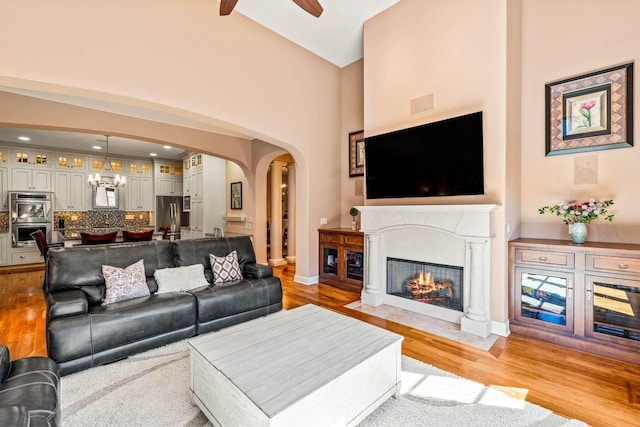 living area with arched walkways, a fireplace with flush hearth, and light wood-style flooring