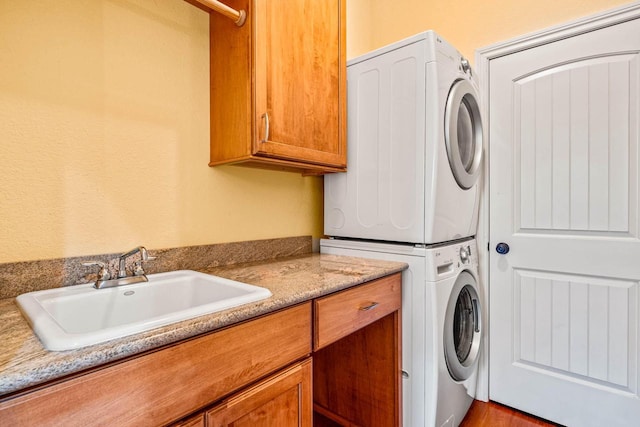 washroom with a sink, cabinet space, and stacked washer and dryer