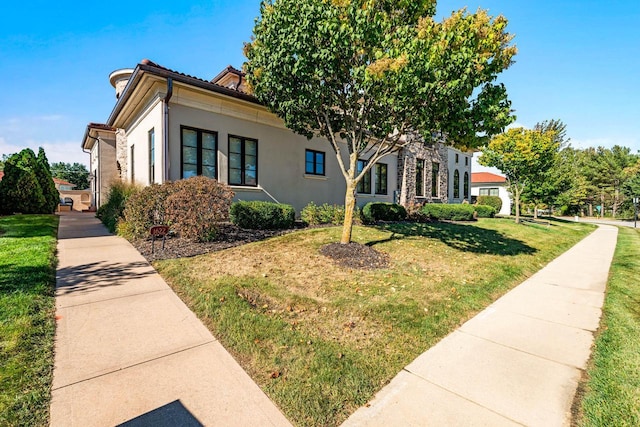 view of side of home featuring stucco siding, a tile roof, and a yard