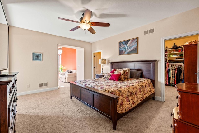 bedroom with a spacious closet, visible vents, and light carpet