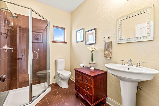 full bath with baseboards, a stall shower, a sink, tile patterned floors, and toilet