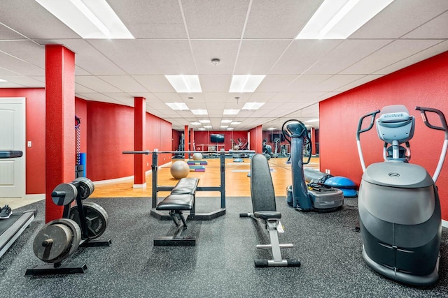 gym with a drop ceiling and baseboards