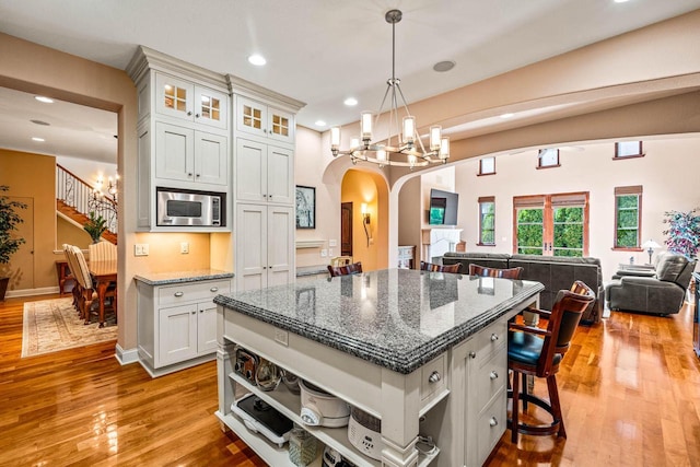 kitchen featuring a notable chandelier, stainless steel microwave, a breakfast bar, and open floor plan