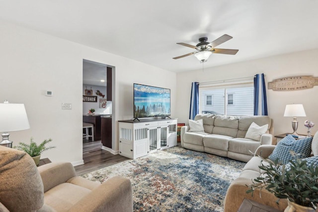 living area with a ceiling fan, baseboards, and wood finished floors