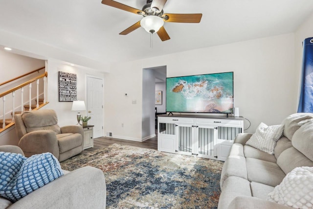 living area featuring ceiling fan, stairway, baseboards, and wood finished floors