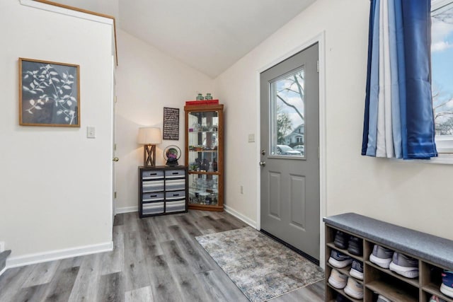 foyer entrance with baseboards, vaulted ceiling, and wood finished floors