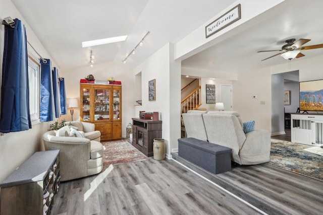 living room featuring vaulted ceiling with skylight, stairway, and wood finished floors