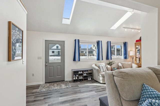 entryway featuring lofted ceiling with skylight, baseboards, and wood finished floors