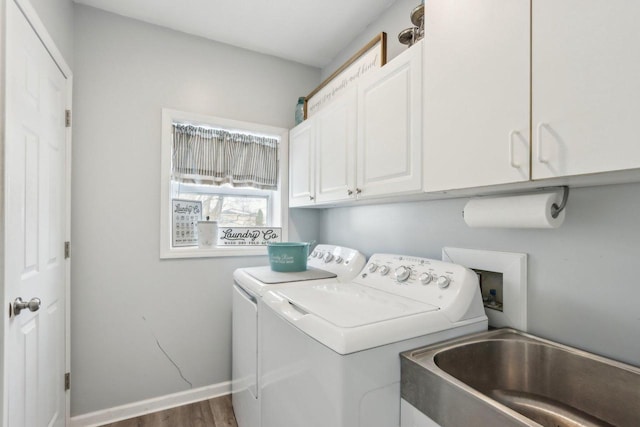 clothes washing area featuring a sink, wood finished floors, baseboards, cabinet space, and washer and clothes dryer