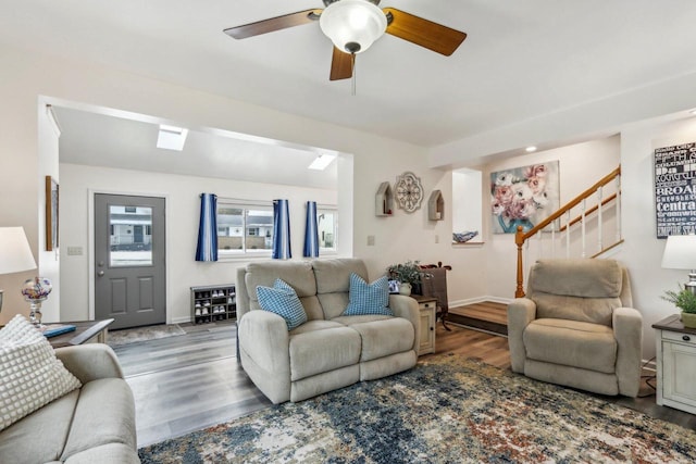 living room with ceiling fan, stairway, baseboards, and wood finished floors