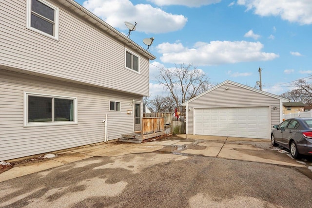 view of side of property with an outdoor structure, fence, and a detached garage