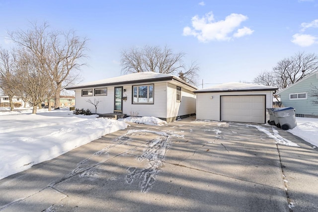 view of front of house featuring driveway, a detached garage, and an outbuilding