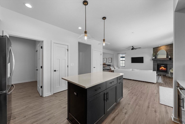 kitchen with light countertops, a fireplace, freestanding refrigerator, and light wood-style floors