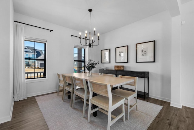 dining space featuring an inviting chandelier, baseboards, and wood finished floors