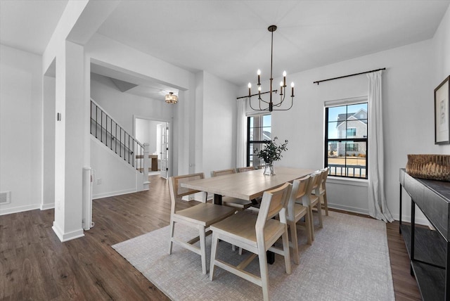 dining room featuring visible vents, stairway, wood finished floors, a chandelier, and baseboards