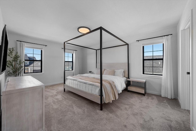 bedroom featuring light colored carpet, baseboards, and multiple windows