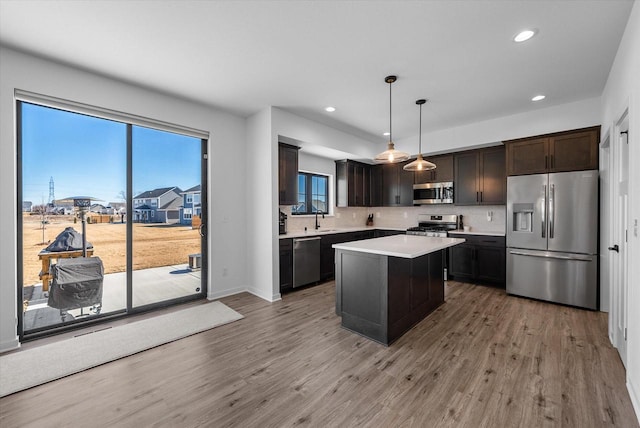 kitchen featuring light countertops, appliances with stainless steel finishes, a sink, dark brown cabinetry, and wood finished floors