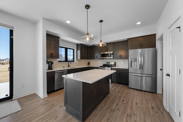 kitchen featuring appliances with stainless steel finishes, a sink, light wood-style flooring, and dark brown cabinets