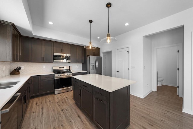 kitchen featuring stainless steel appliances, light wood-type flooring, backsplash, and dark brown cabinetry