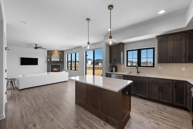 kitchen featuring tasteful backsplash, a fireplace, a sink, and dark brown cabinetry