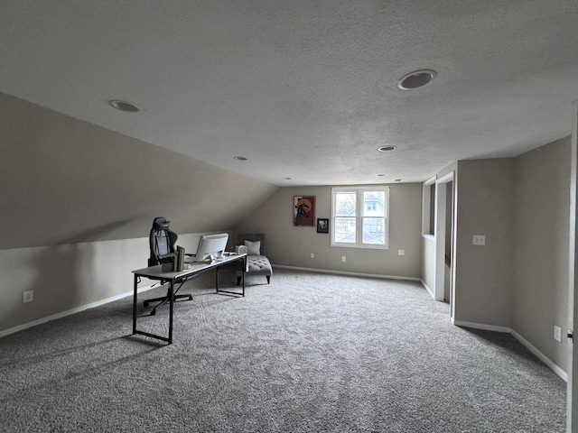 unfurnished office with lofted ceiling, carpet, baseboards, and a textured ceiling