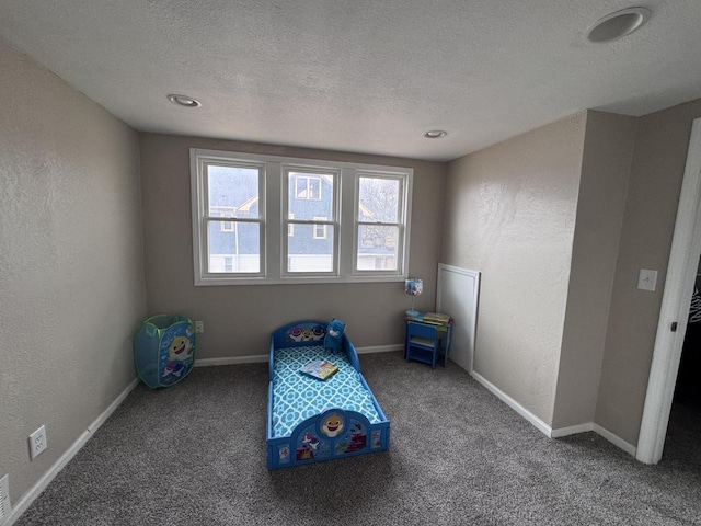 game room featuring baseboards, a textured ceiling, and a textured wall