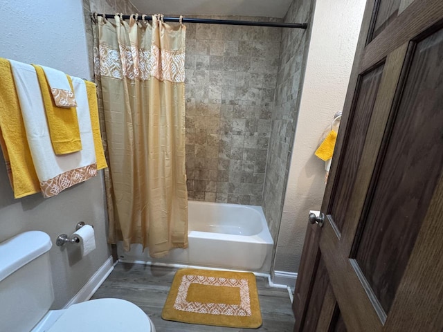 bathroom with baseboards, a textured wall, toilet, wood finished floors, and shower / bath combination with curtain