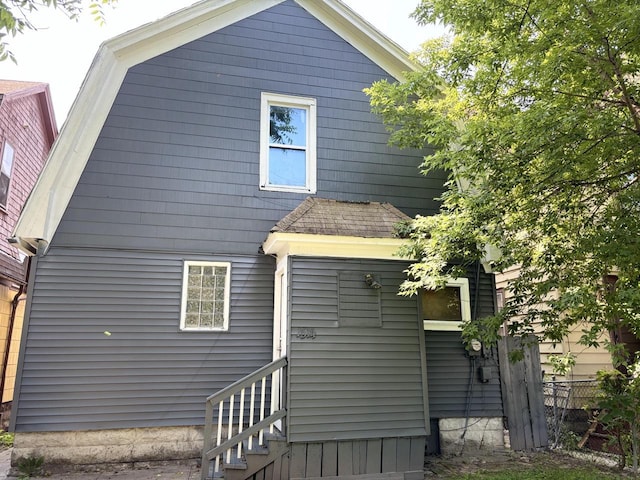 back of house with entry steps, fence, and a gambrel roof