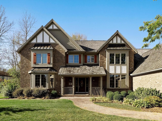 view of front of home with metal roof, a standing seam roof, a front lawn, a porch, and brick siding