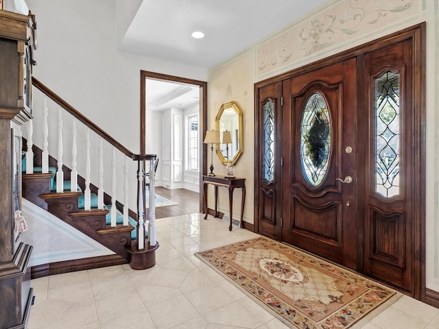 foyer entrance featuring light tile patterned floors, stairs, and baseboards