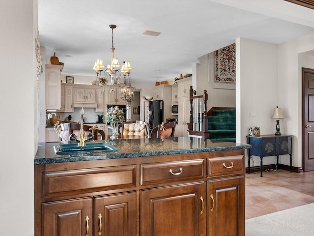 kitchen featuring a chandelier, a sink, baseboards, hanging light fixtures, and freestanding refrigerator