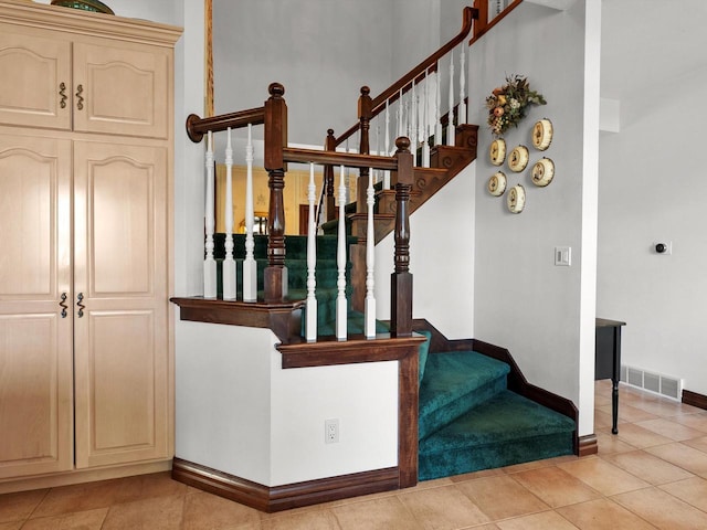 stairway featuring baseboards, visible vents, and tile patterned flooring