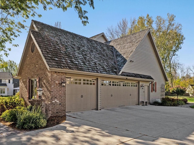 view of side of home featuring a garage, concrete driveway, and brick siding