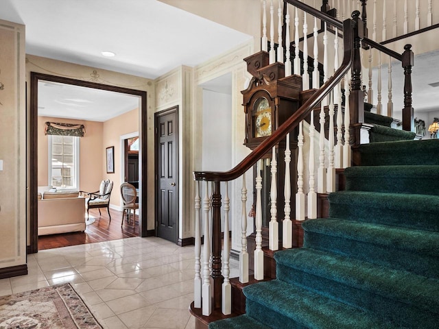 stairway with baseboards and tile patterned floors