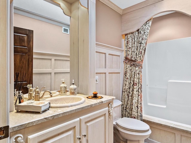 bathroom with a shower with shower curtain, toilet, a wainscoted wall, vanity, and a decorative wall