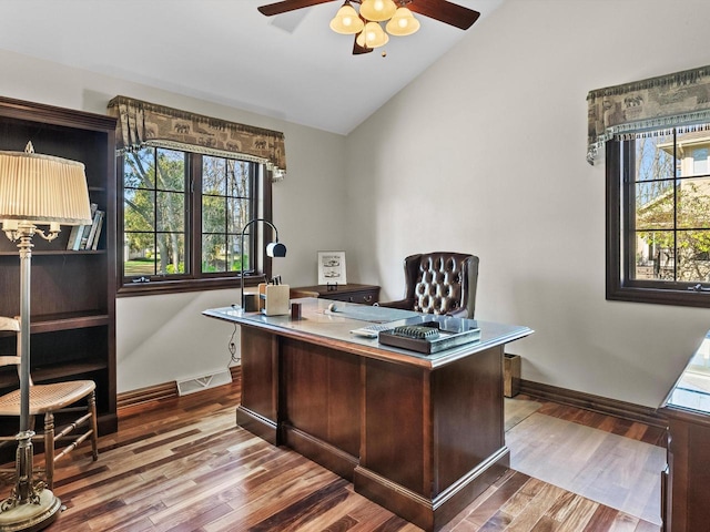 office featuring lofted ceiling, visible vents, a ceiling fan, wood finished floors, and baseboards