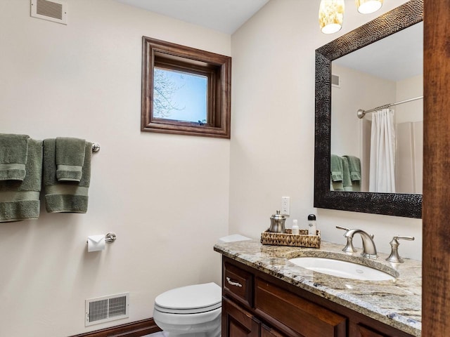 bathroom featuring toilet, curtained shower, visible vents, and vanity