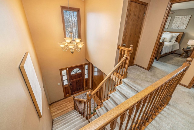 carpeted entrance foyer featuring a chandelier and baseboards