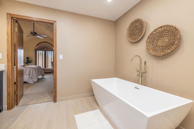 ensuite bathroom featuring lofted ceiling, ensuite bathroom, wood finished floors, a freestanding tub, and baseboards