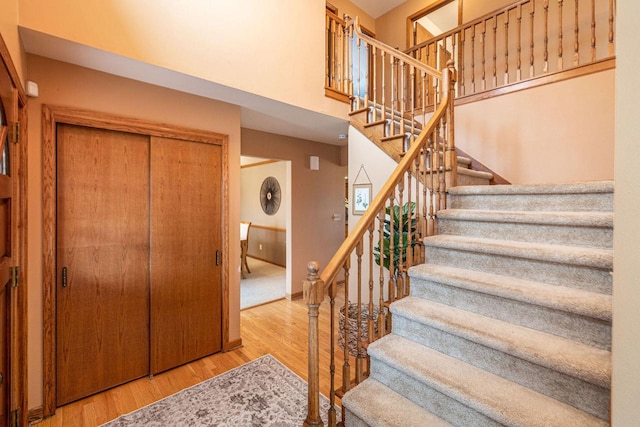 staircase featuring a high ceiling, wood finished floors, and baseboards